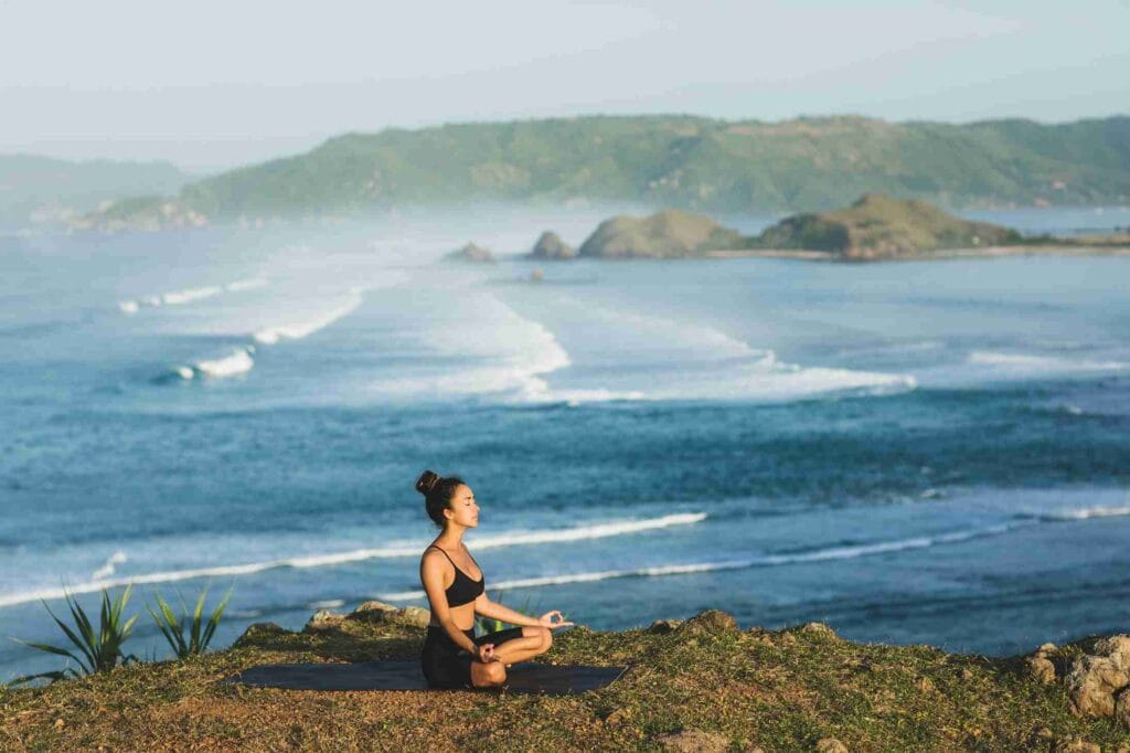 Person meditating by the ocean.