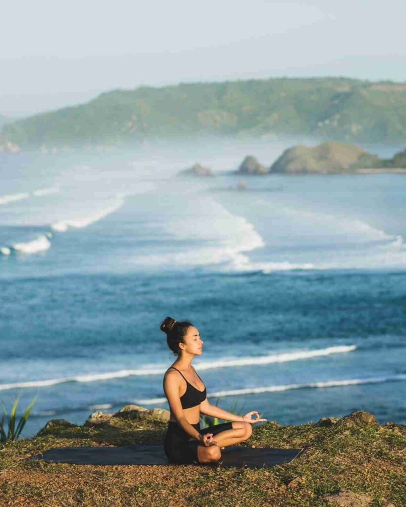 Person meditating by the ocean.